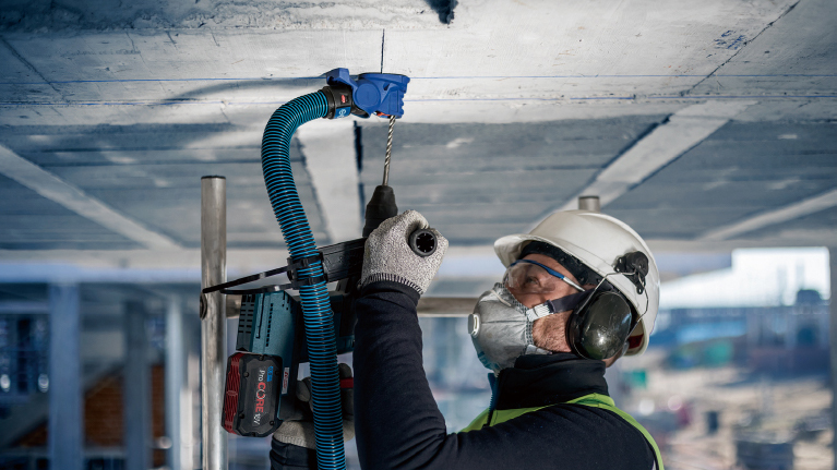 A craftsman is drilling into a ceiling with a Bosch Professional tool.