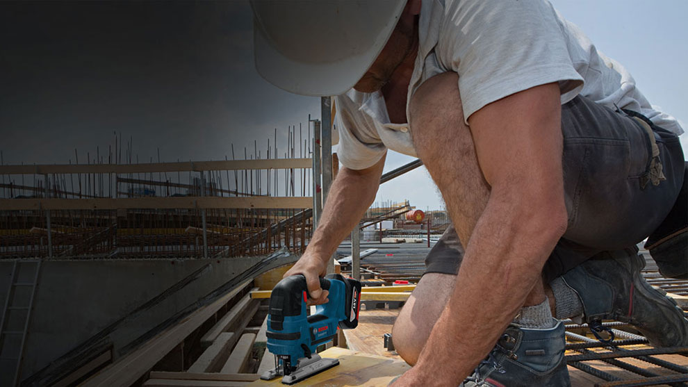 A worker is using a Bosch Professional jigsaw on a construction site.