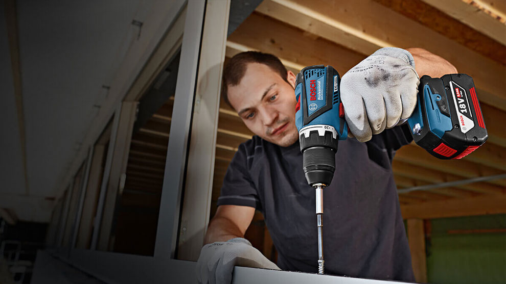 A man with a Bosch Professional cordless drill is assembling a metal profile.