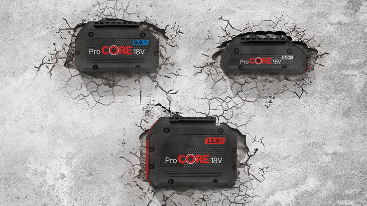 Three Bosch ProCORE 18V batteries are lying on a cracked concrete floor.