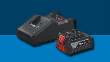 A black Bosch Professional charger lies next to a black 18V battery with a red label on a blue background.