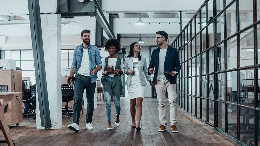 Four people are walking together in a modern office.