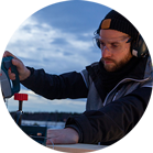 A man with headphones is cutting wood with a Bosch saw outdoors.