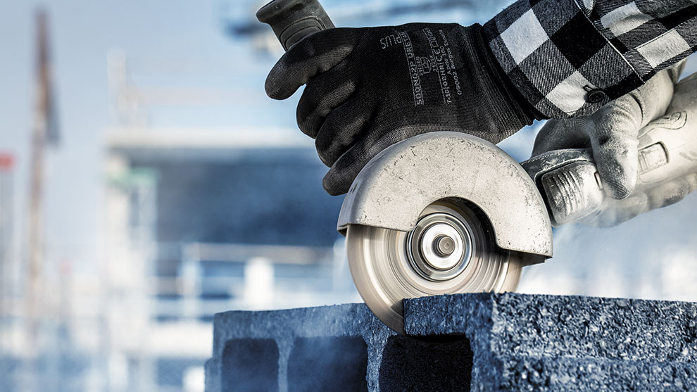 A person is cutting gray stones with a cutting machine.