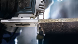 A Bosch Professional jigsaw is cutting through a wooden board.