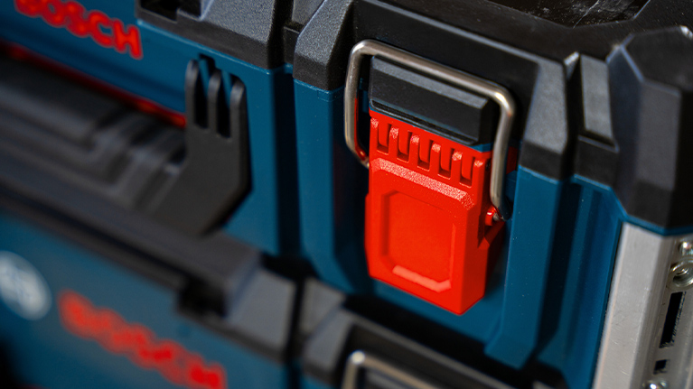 Close-up of a blue toolbox with a red latch and silver holder.