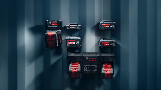 Six Bosch Professional batteries in red-black color are mounted on a textured wall.
