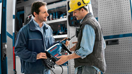 Two men in work clothes are showing a Bosch Professional tool.