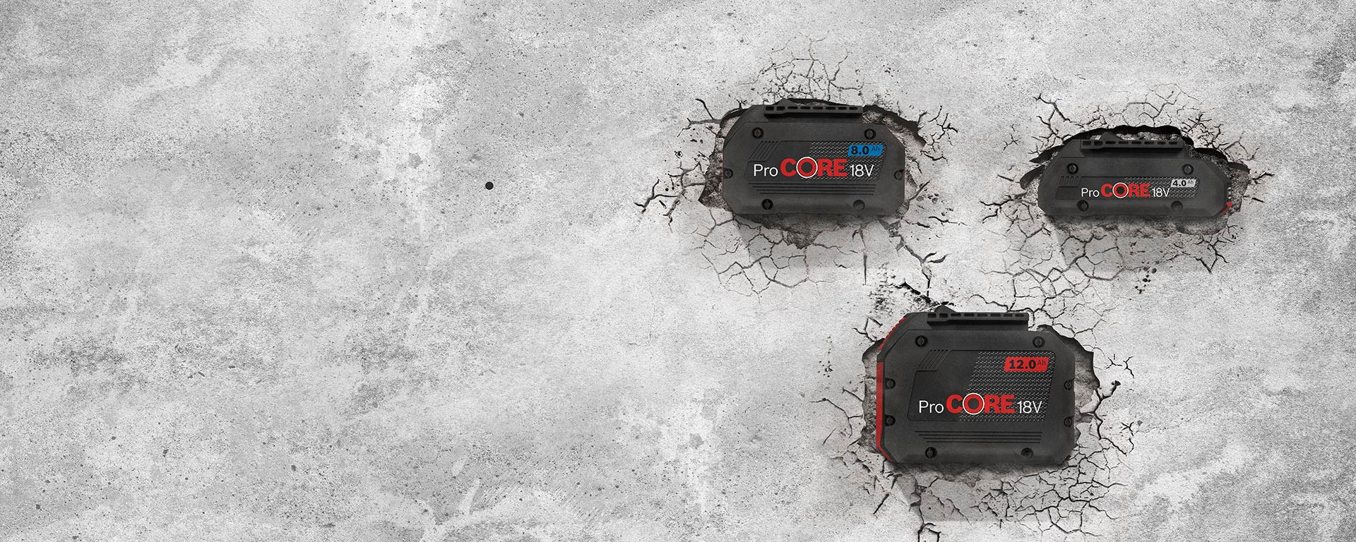 Three Bosch ProCORE 18V batteries in black on gray concrete.